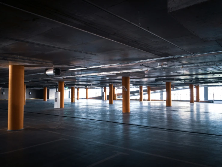 an empty building with yellow columns and empty parking lot