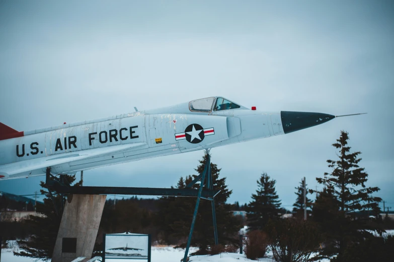 a military jet on display in the middle of a forest