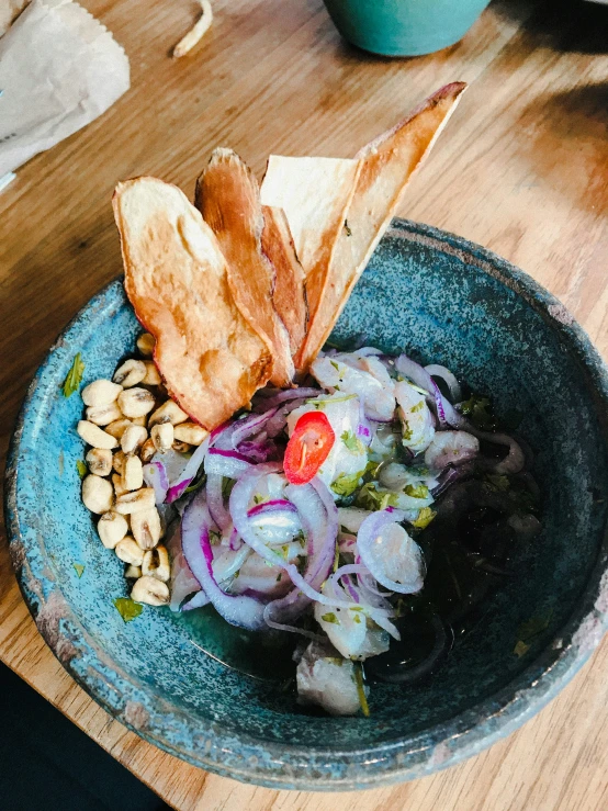 a bowl on a table has a tortilla and salad inside of it