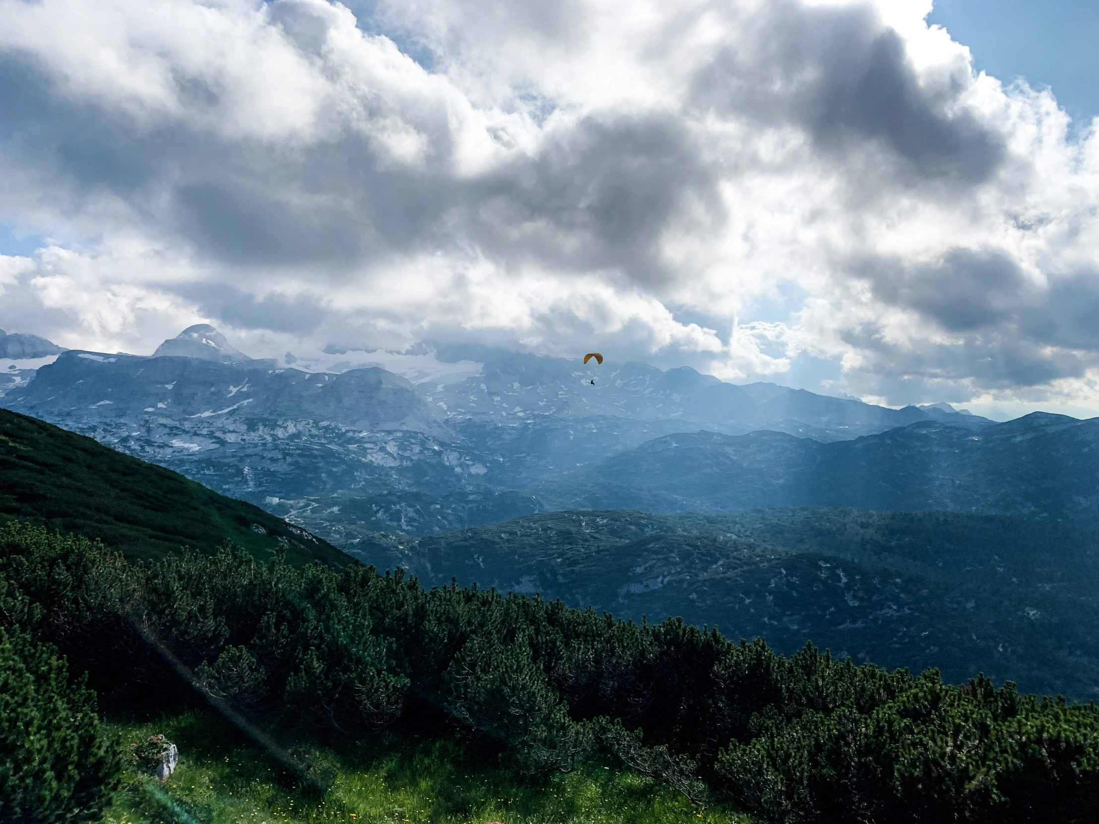 a parasailer is flying through the air over a mountain range