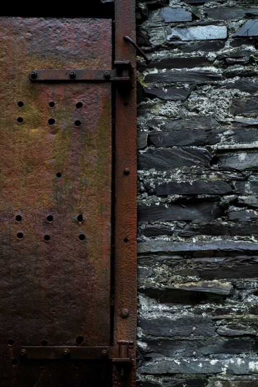 a rusted steel door with a brick wall behind it