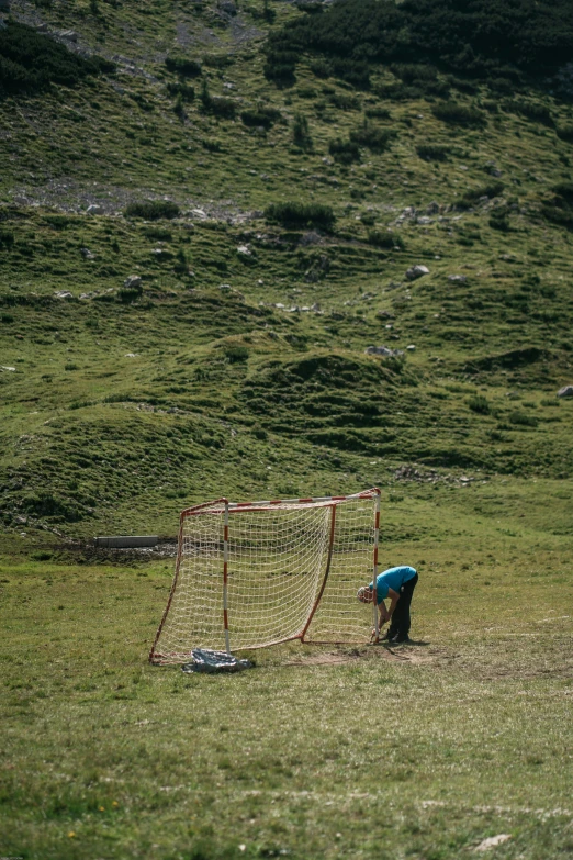 a soccer goal with a  crouching down on the grass