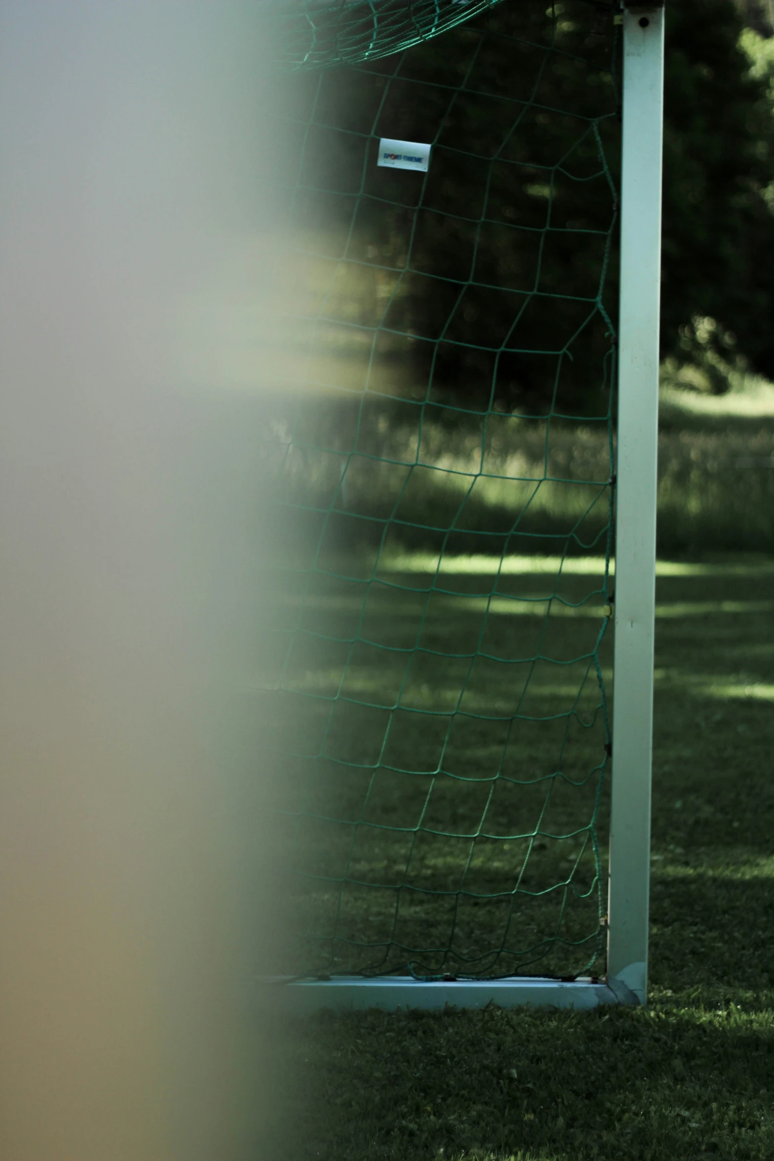 a soccer goal sits on the grass in front of a net