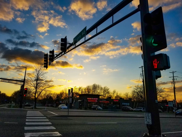 a street with traffic lights and signs against a sunset sky