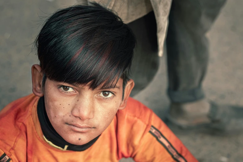 a little boy who is wearing an orange and black outfit