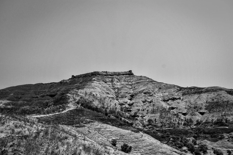 black and white landscape of a mountain with hills, trees and a cloudy sky