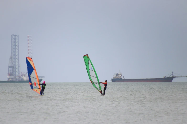 two people wind sailing in the ocean on a very overcast day