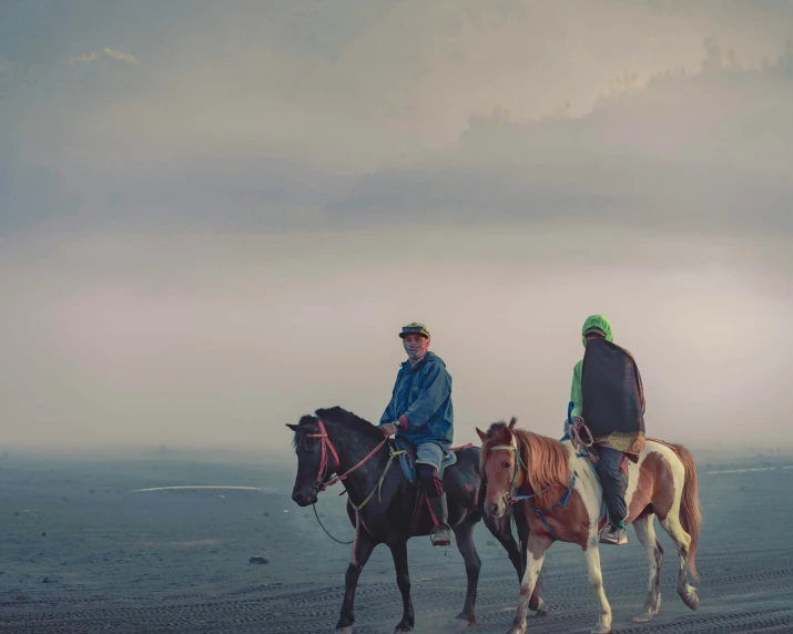 two men ride their horses in the desert