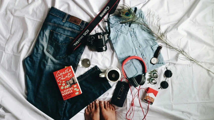 the contents of a purse, sunglasses, and jeans laid out on a sheet