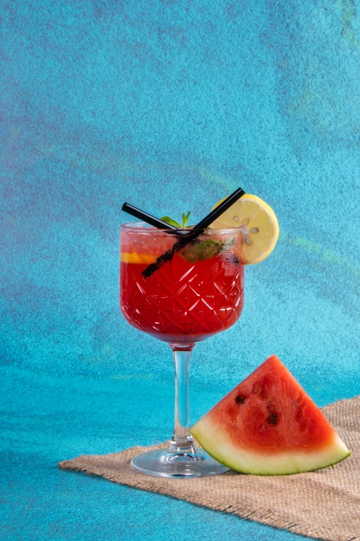 a glass filled with a red drink and slices of watermelon