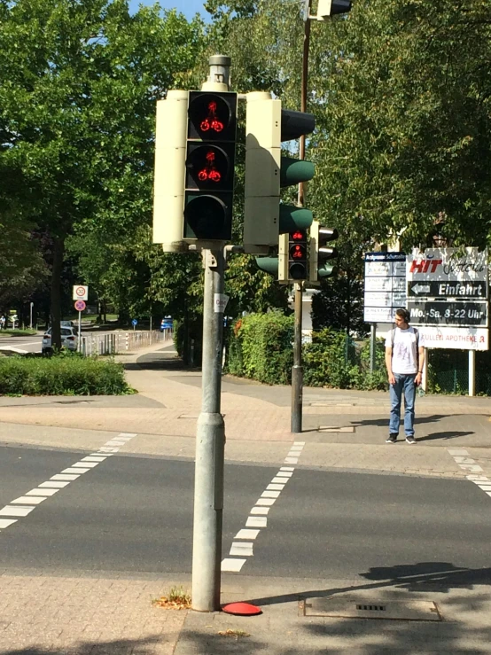 a traffic light next to a man walking on a sidewalk