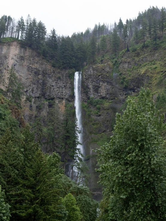 a waterfall with a few people standing in front of it