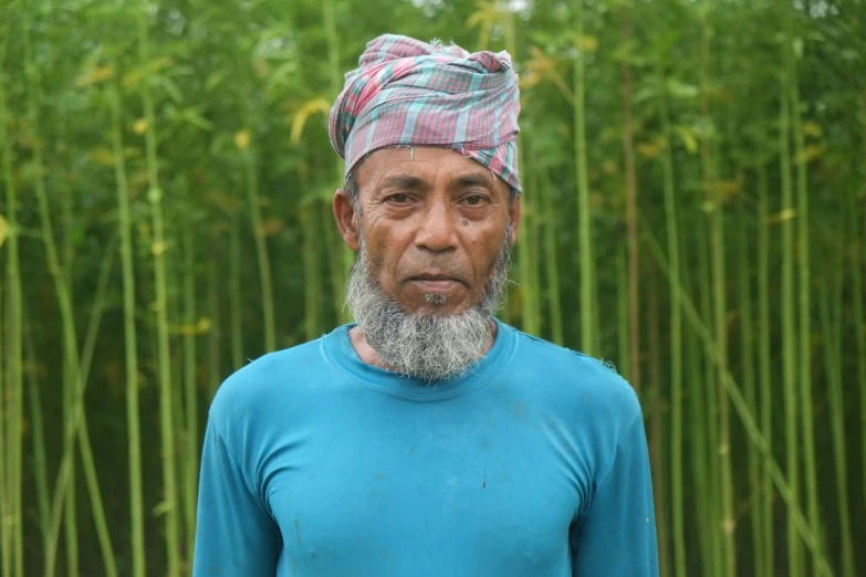 a man wearing a blue shirt stands in front of a bamboo forest