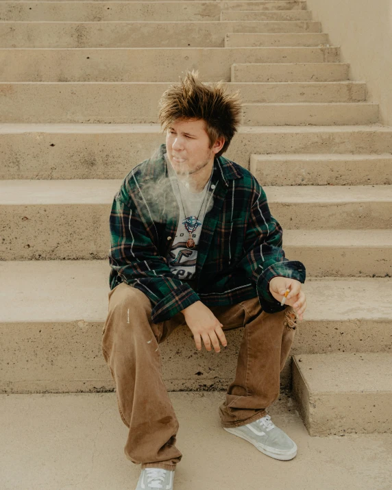 the young man is sitting on the stairs smoking