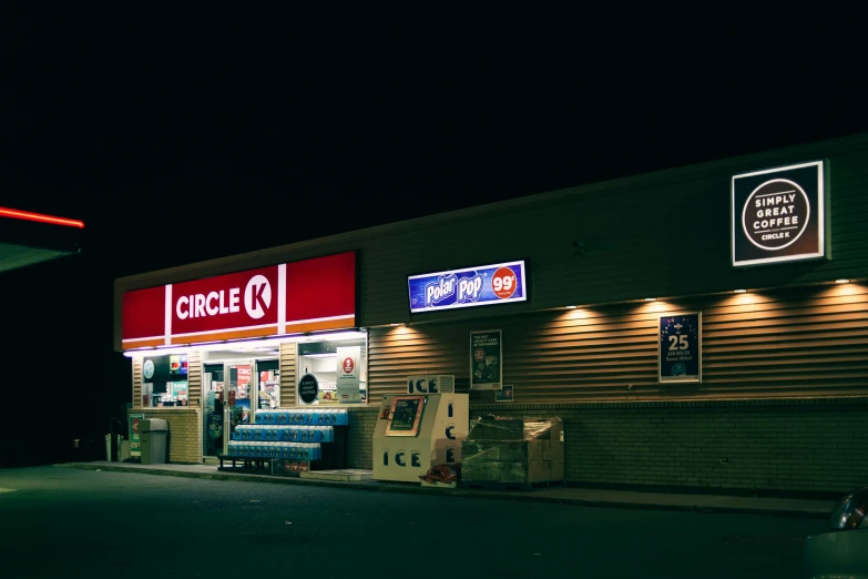 a store front at night with an illuminated sign and a red light