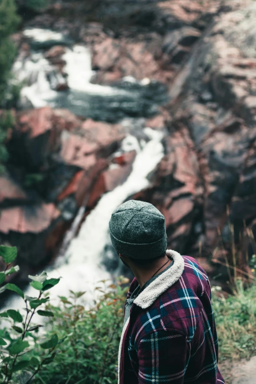 a man looking down at a river running through the rocks