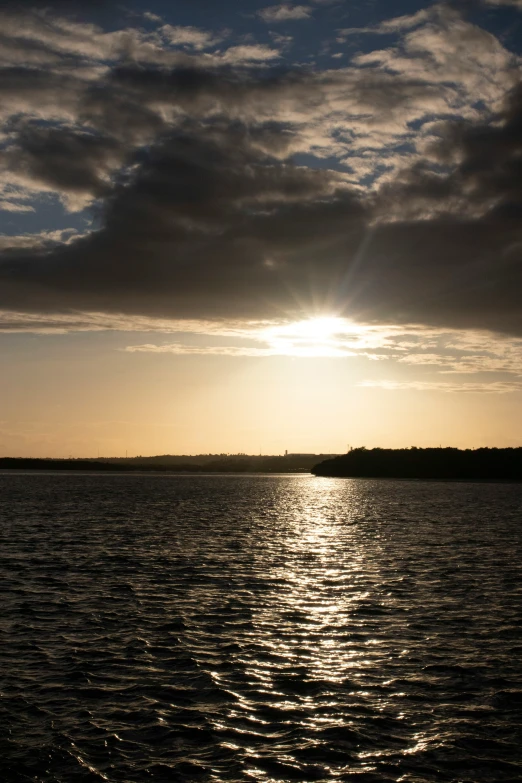 the sun reflecting in water with a very dark sky