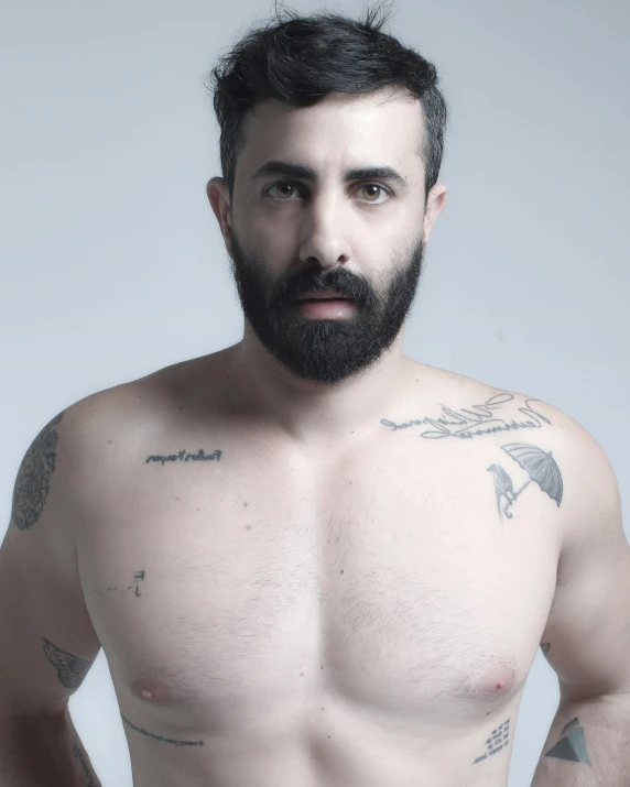 a shirtless man with black hair and a beard