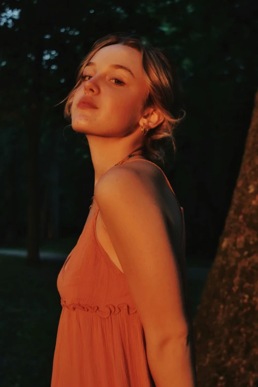 a woman in an orange dress looks up at the sky