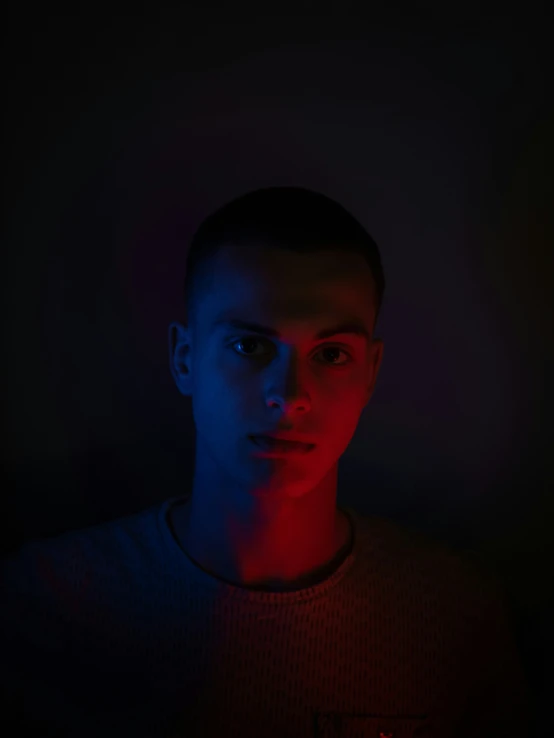 a man looking at a camera with red and blue light in the background