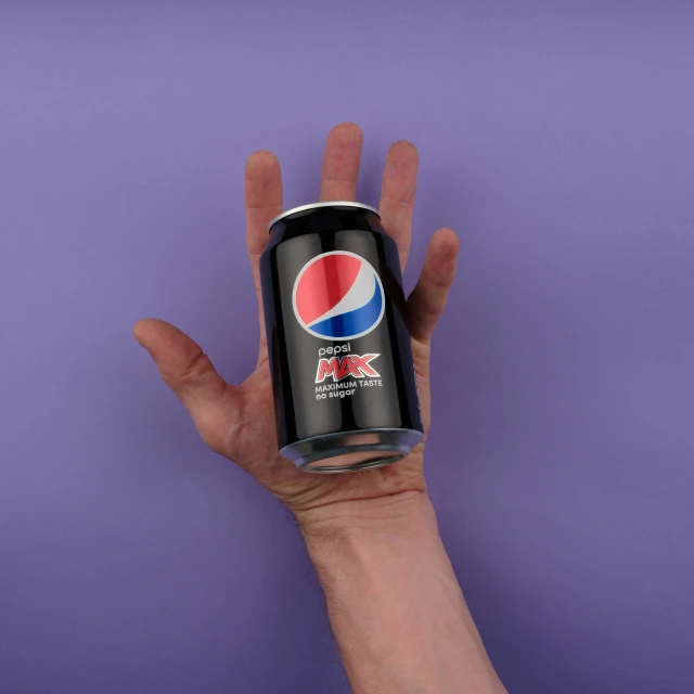 a person's hand holding a can of pepsi