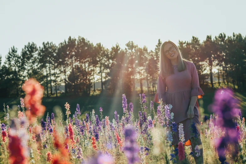 a woman is standing in a field full of flowers