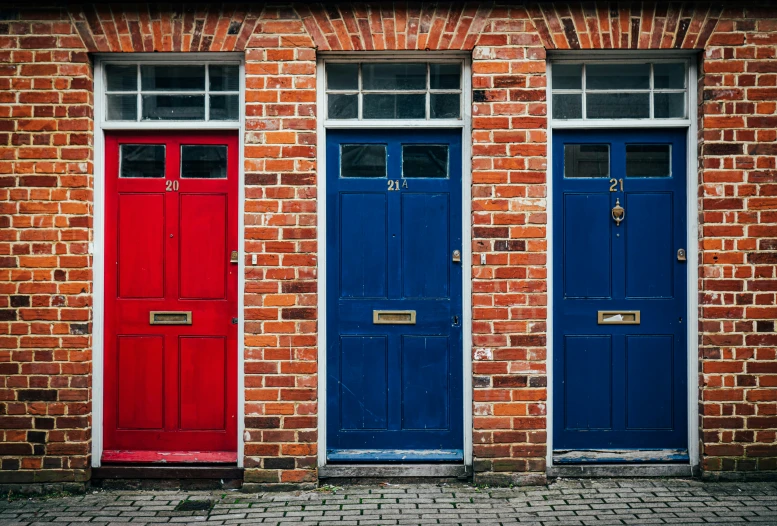 two blue red and one red doors a brick building