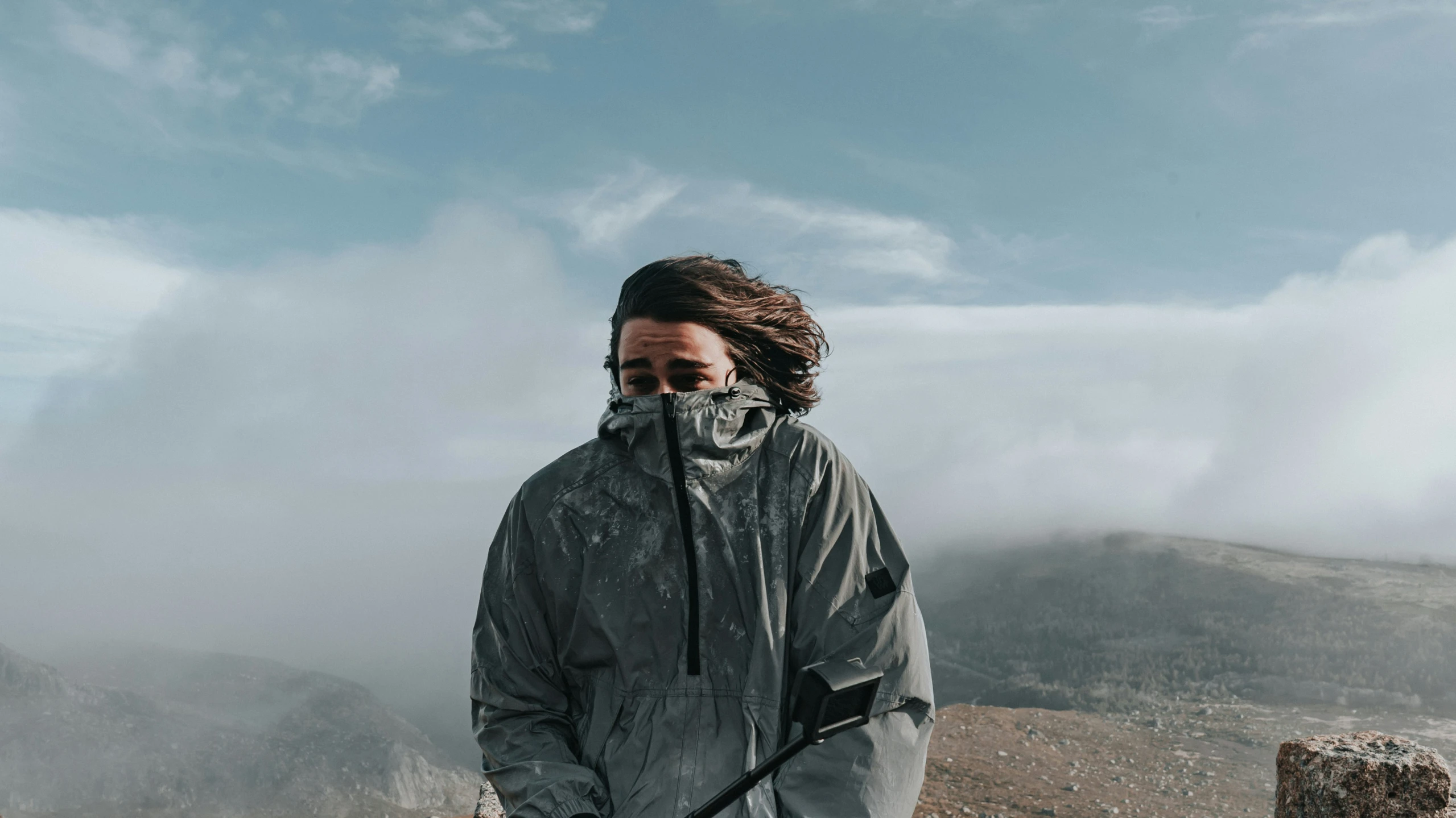 man with hood up walking in the mountains