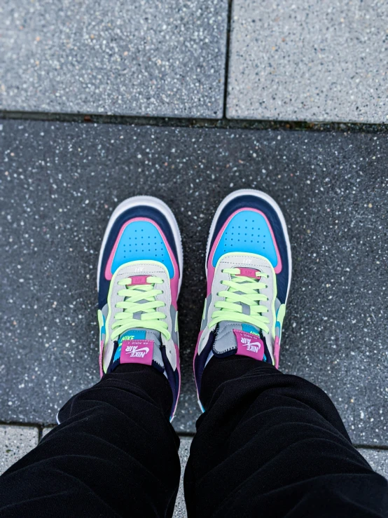 a pair of feet in black jeans with bright colored shoes