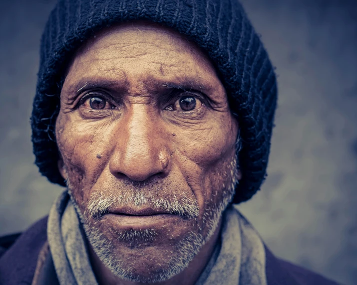 an old man has grey hair and wearing a black knitted hat