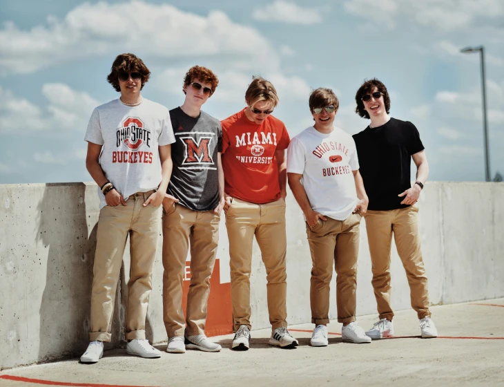 four boys on a cement wall holding orange skateboards