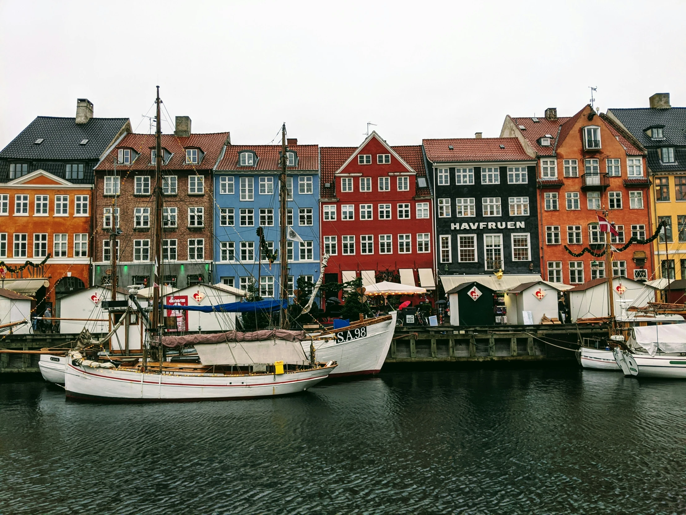 several boats sitting at the dock in front of tall houses