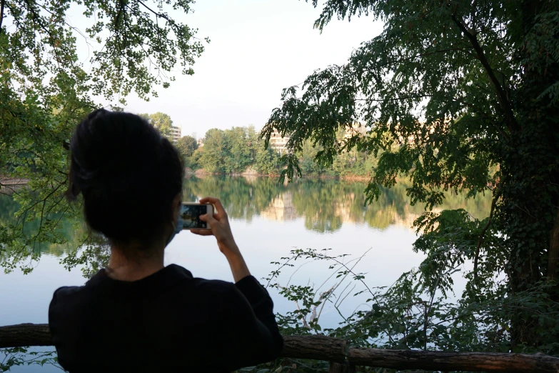 a woman takes a picture of the lake through her phone