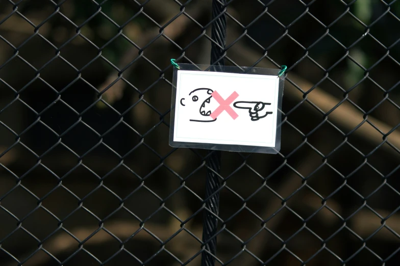a sign attached to a wire fence with graffiti on it