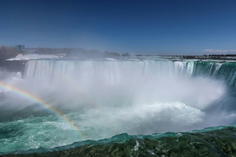 a rainbow shines over the water at victoria falls