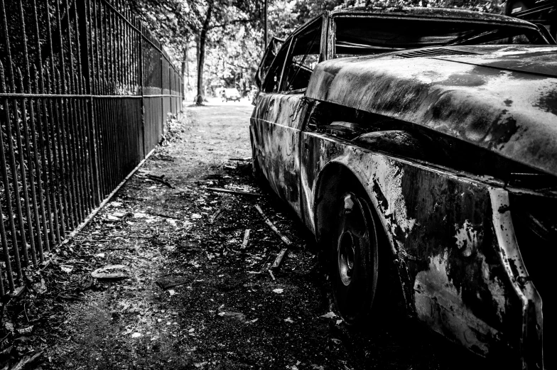black and white pograph of an old car parked by a fence