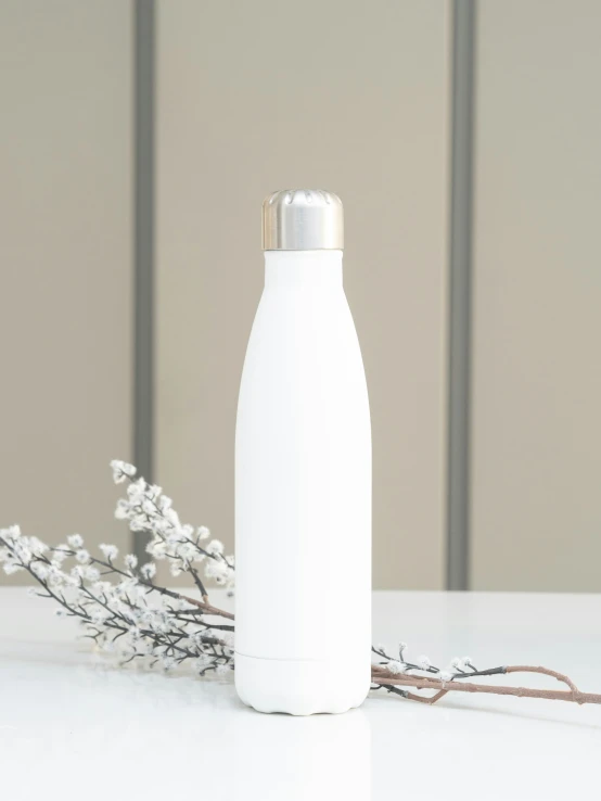 a white water bottle sitting on top of a table next to small flowers