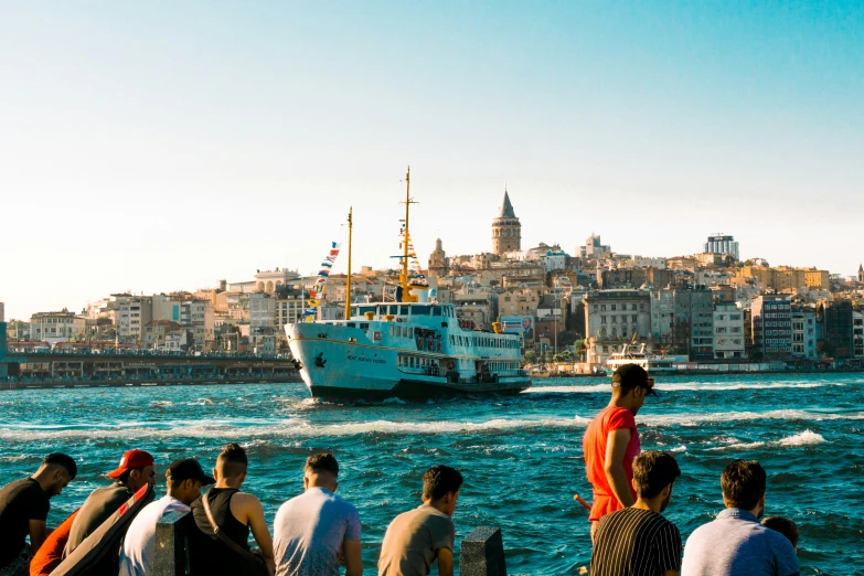 a group of people looking at a ship on the ocean