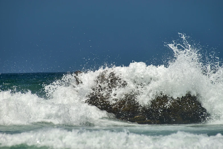 some very pretty waves near some rocks by the ocean