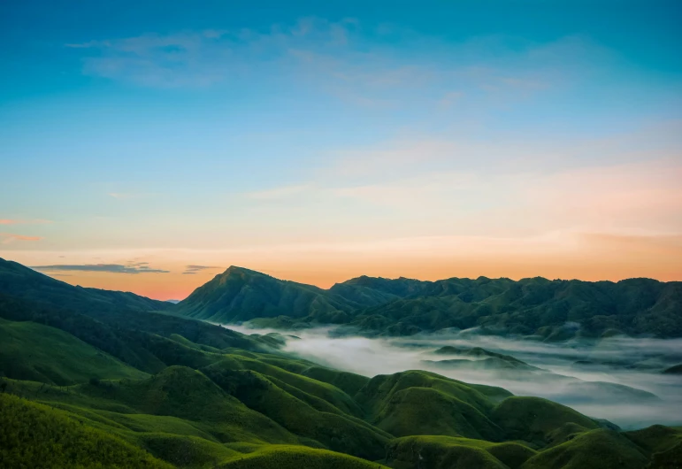 mountains with mist coming out at sunset over them