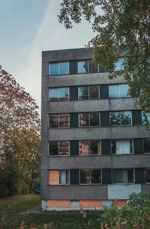 a tall building with windows, sitting under trees