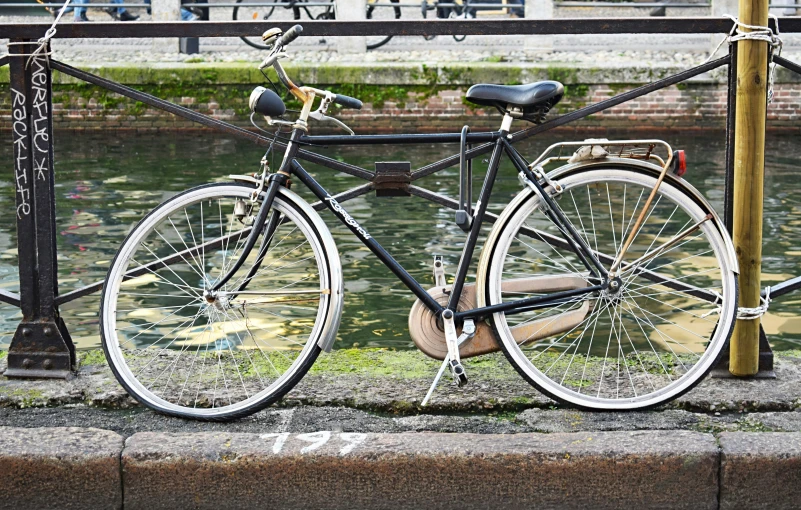 a black and white bicycle parked next to a lake