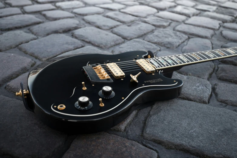 a black guitar sits on the cobblestones