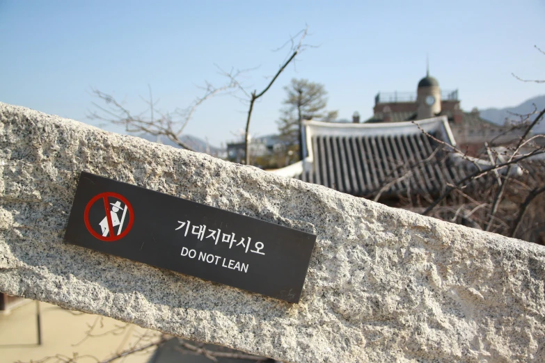 a sign on the side of a rock wall near a building