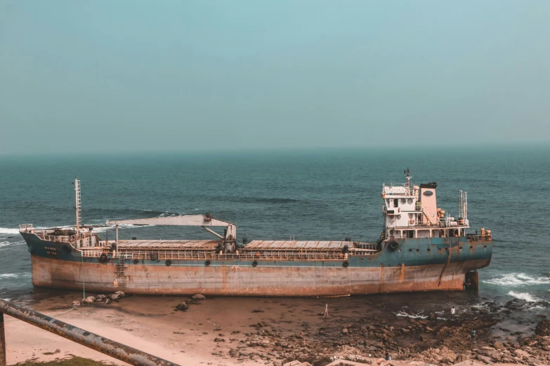 a rusty ship in the water on the shore