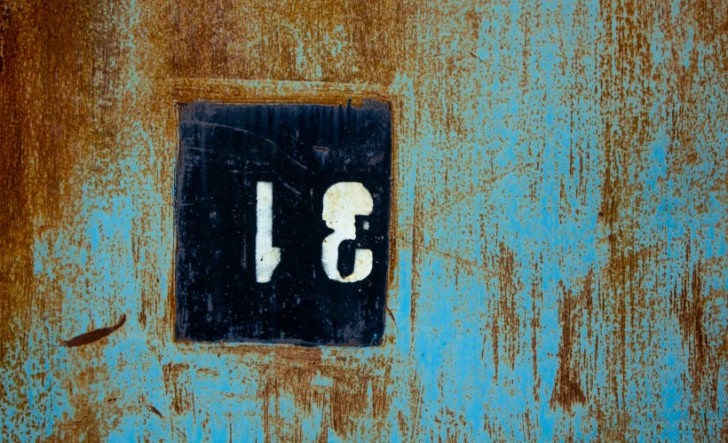 a dirty and scratched down blue wall with a white number 13 on it