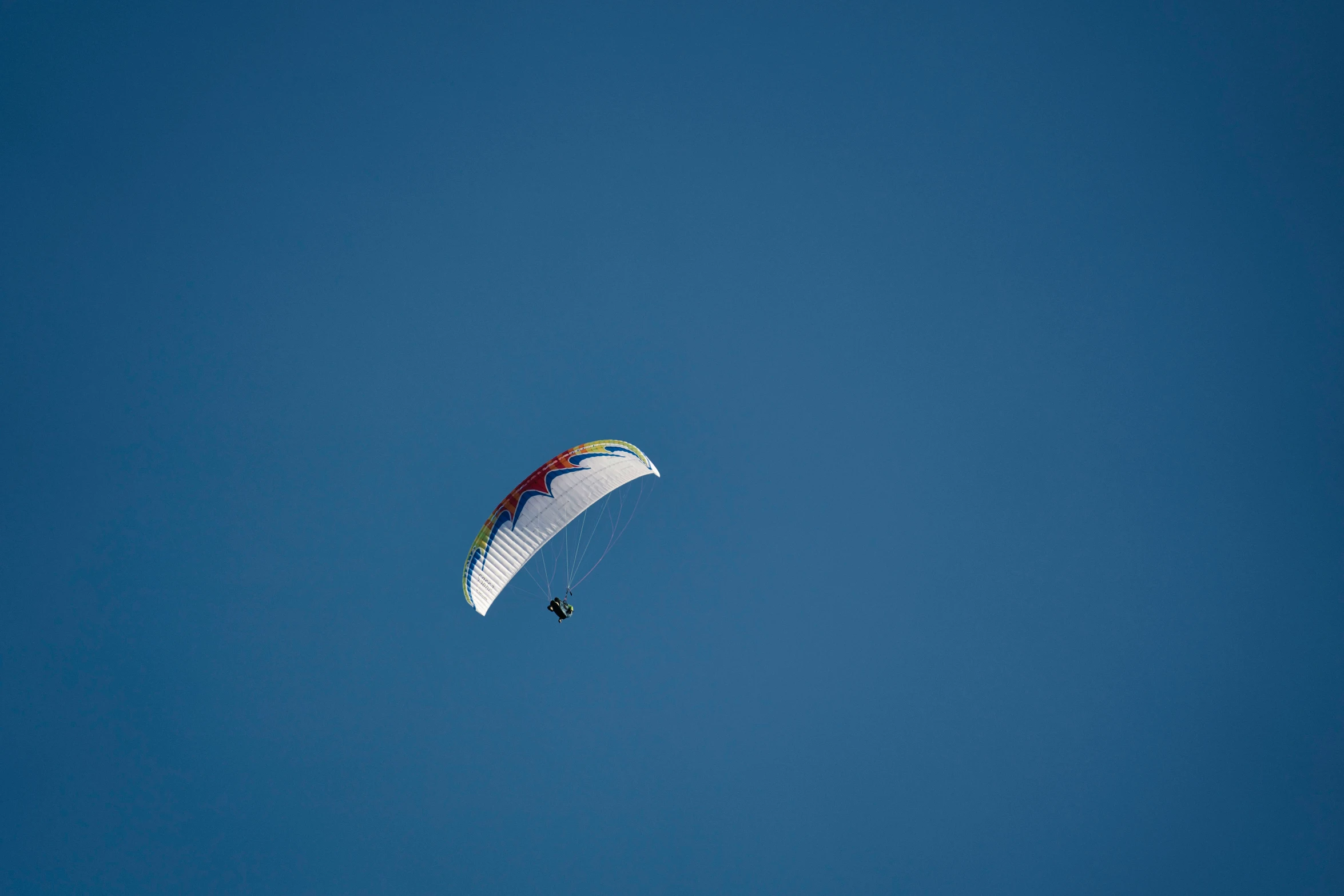 a large white para sail in the blue sky