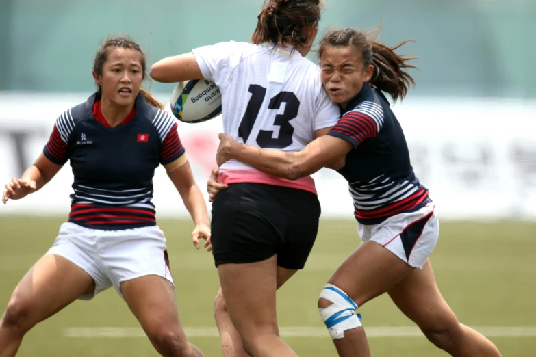 two female rugby players collide as one holds the ball