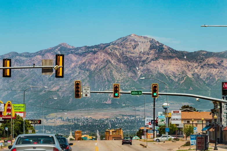 cars and a traffic light on a street by mountains