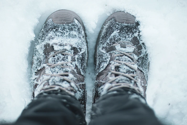 a persons foot in snow covered shoes standing outside